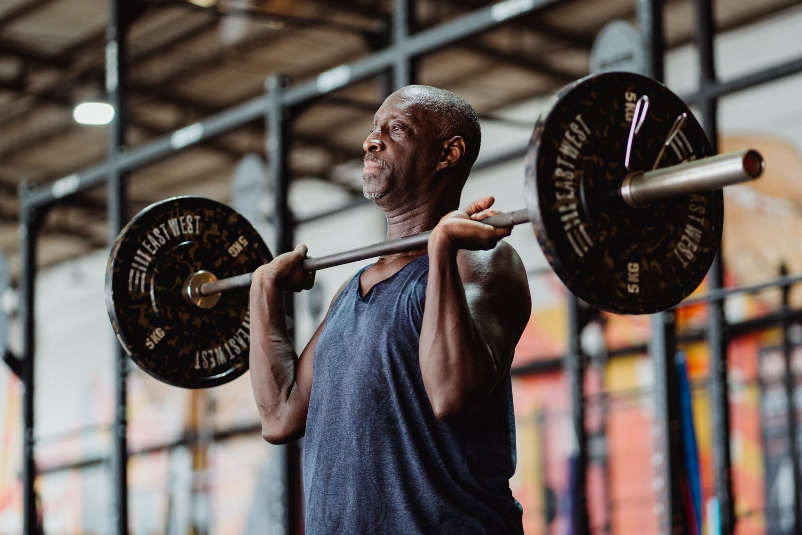A senior man engaged in focused weightlifting at an indoor gym, showcasing strength and fitness.