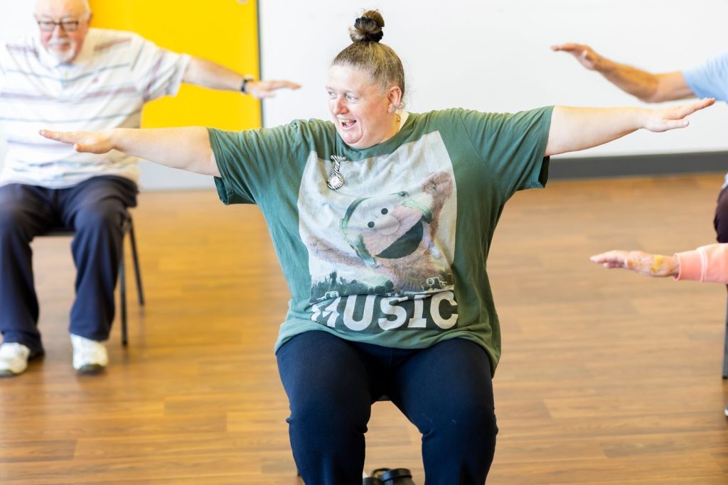 Seniors participating in a seated exercise class, promoting community health and active aging.