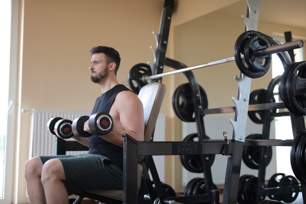 Adult man lifting dumbbells in a gym, focusing on strength and fitness training.