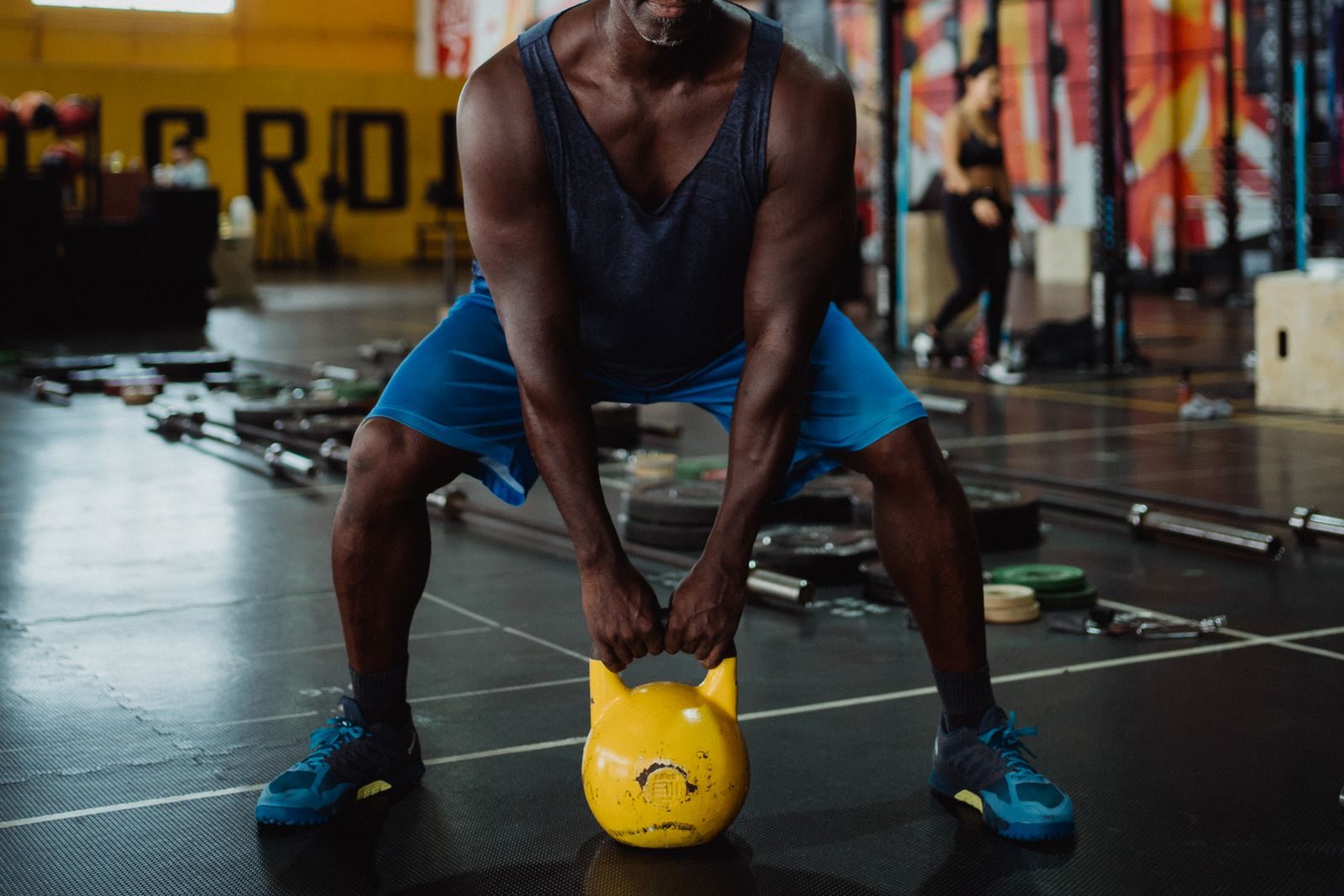 Focused black man performing kettlebell exercise in a modern gym setting for strength training.