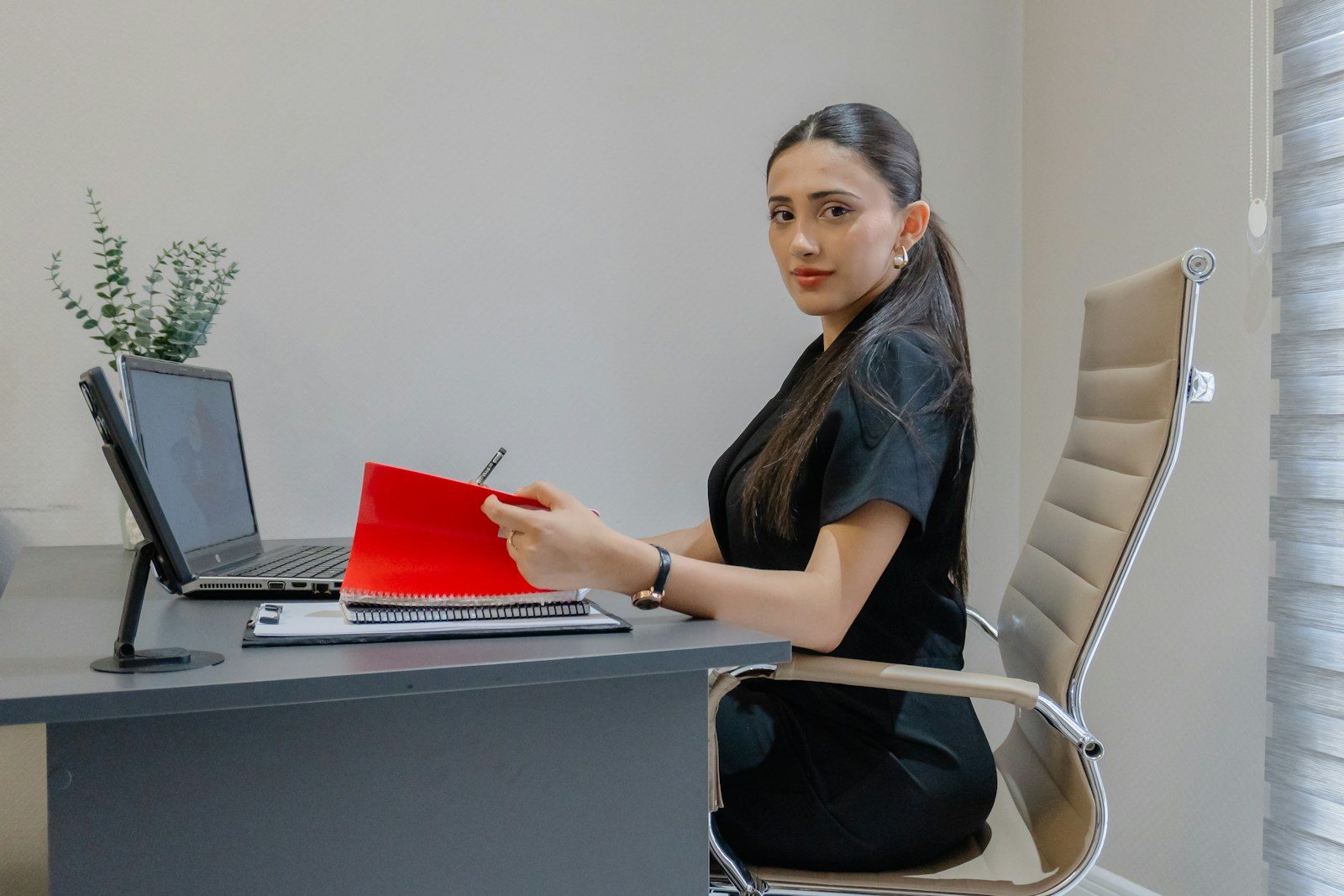 Woman working at desk with laptop and red folder