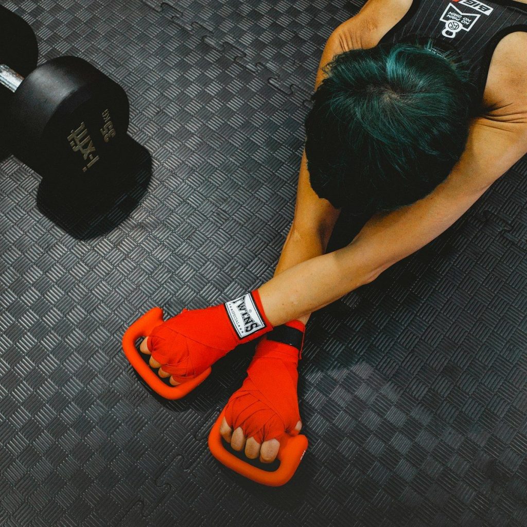 Person stretching with boxing gloves and dumbbell