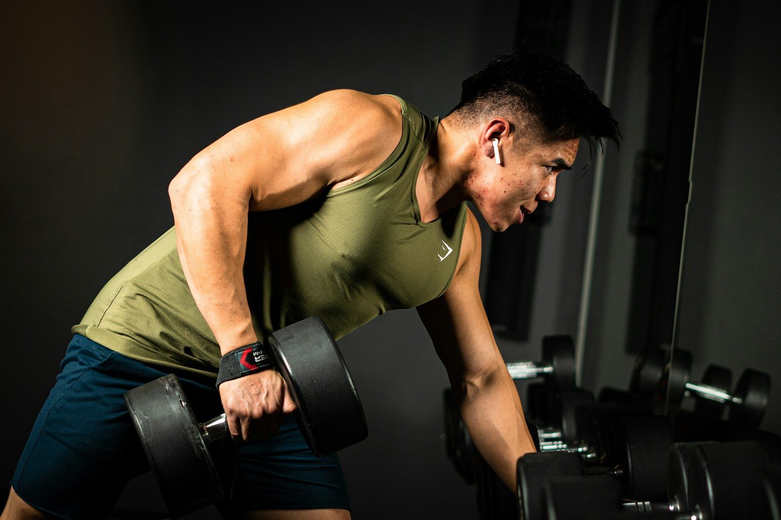a man holding a pair of dumbbells in a gym