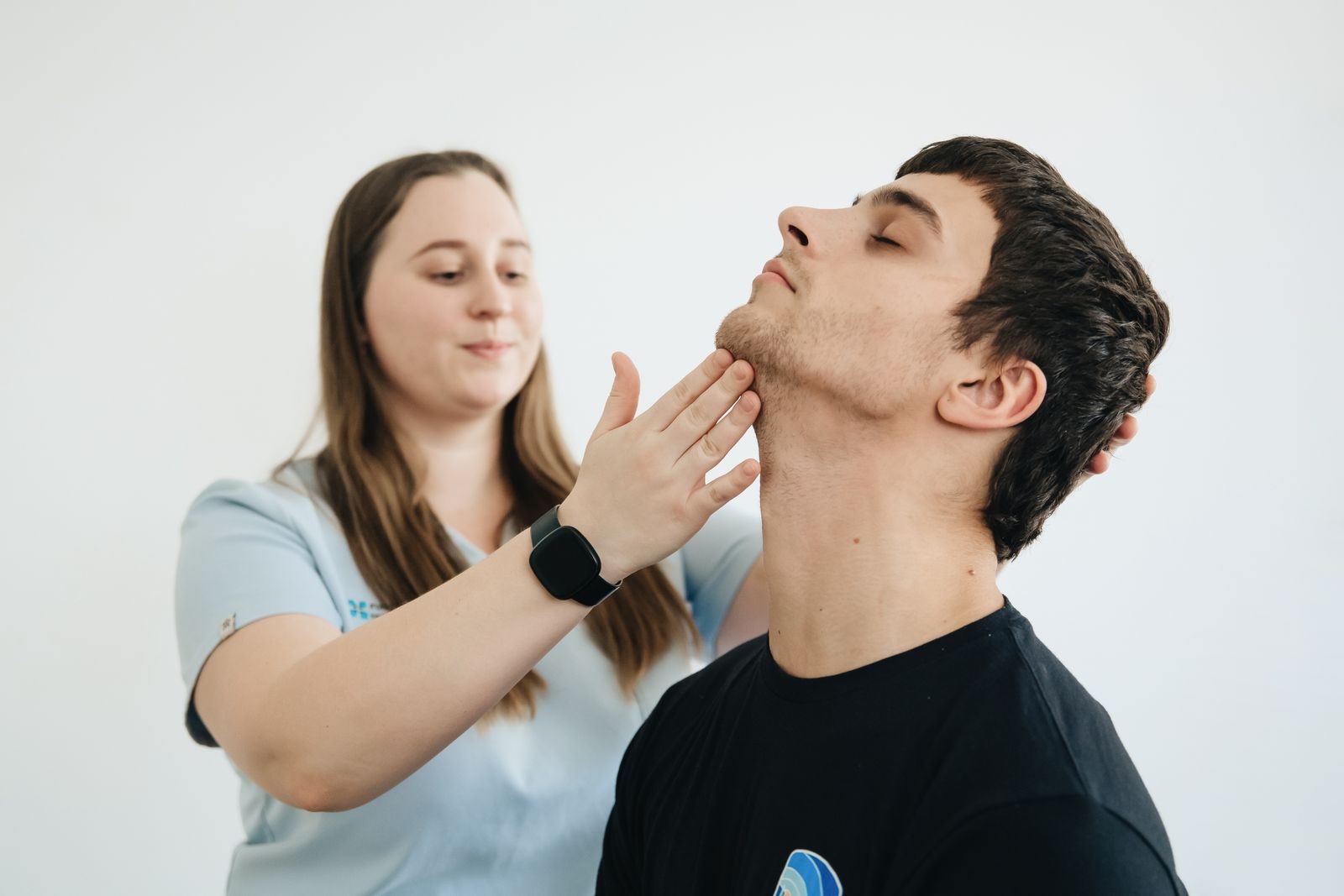 A physiotherapist performs therapy on a male patient's neck in Vilnius clinic.
