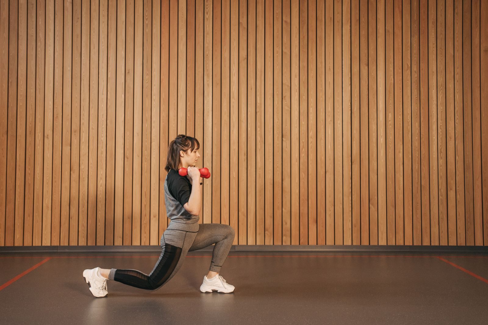 Side view of a woman exercising with dumbbells, promoting fitness and a healthy lifestyle.