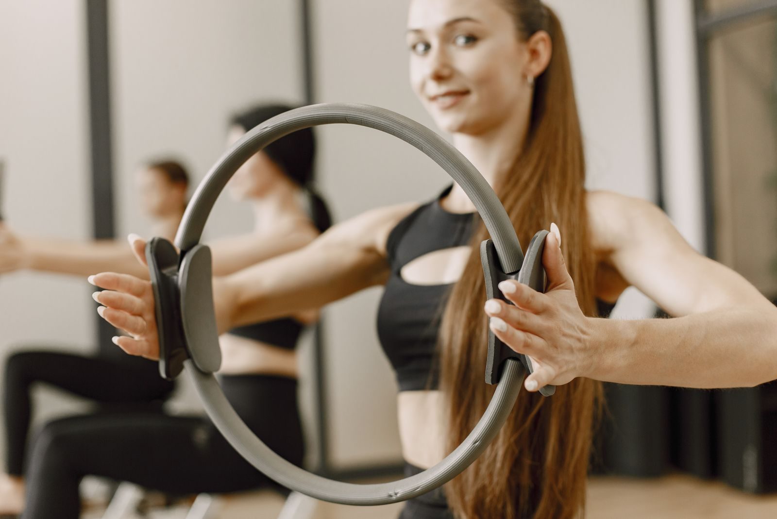 A woman practicing pilates with a magic circle in a fitness studio, focusing on workout.