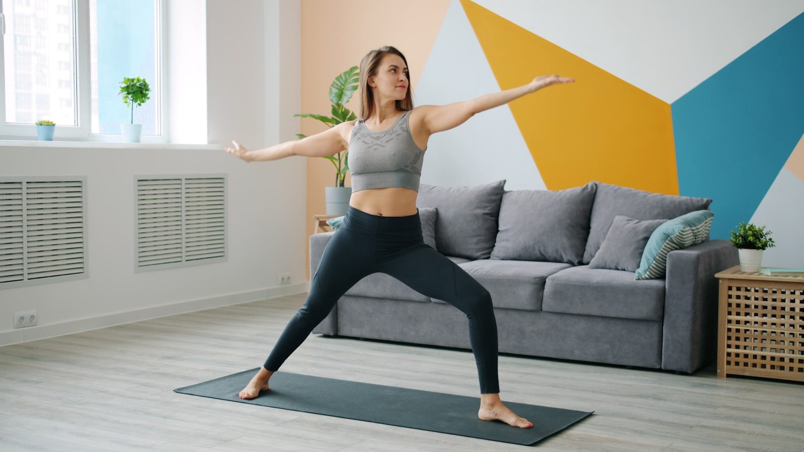 Woman practicing warrior ii pose on yoga mat