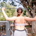 Woman using a resistance band for workout at an outdoor gym, showcasing healthy and active lifestyle.