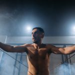 Man exercising with resistance bands in a smoky gym setting. Fitness and strength training.