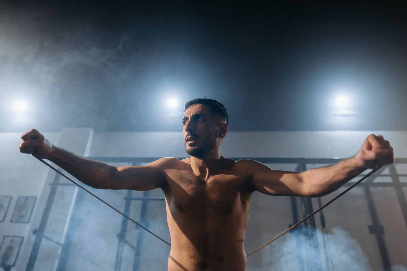 Man exercising with resistance bands in a smoky gym setting. Fitness and strength training.